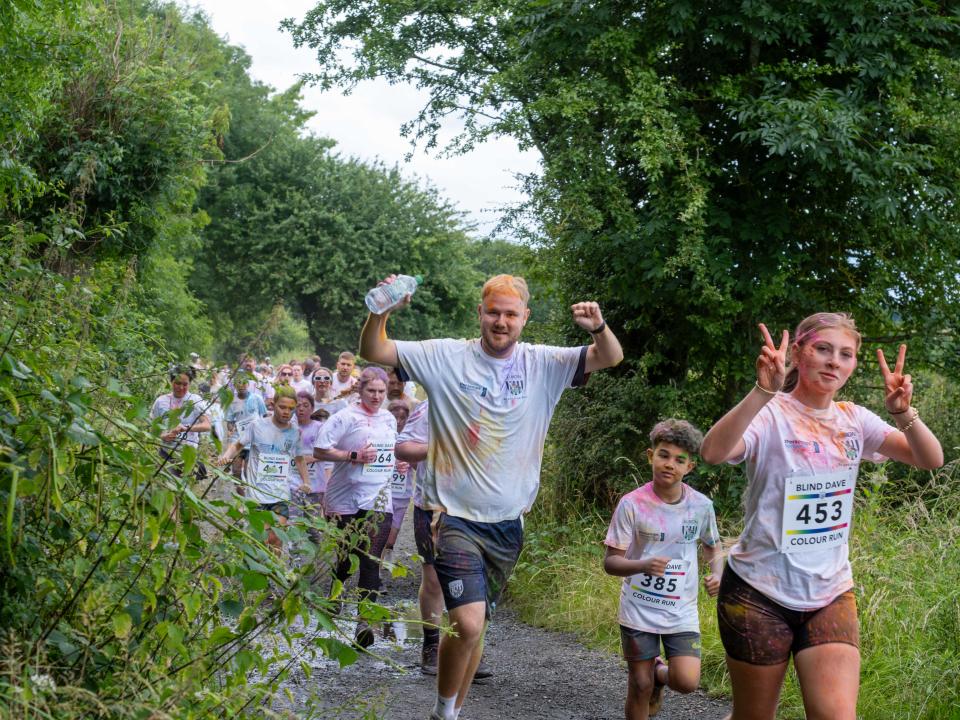 One participant (far right) holding up peace sign with both hand. Another participant holding a water bottle in one hand his fist up in joy.