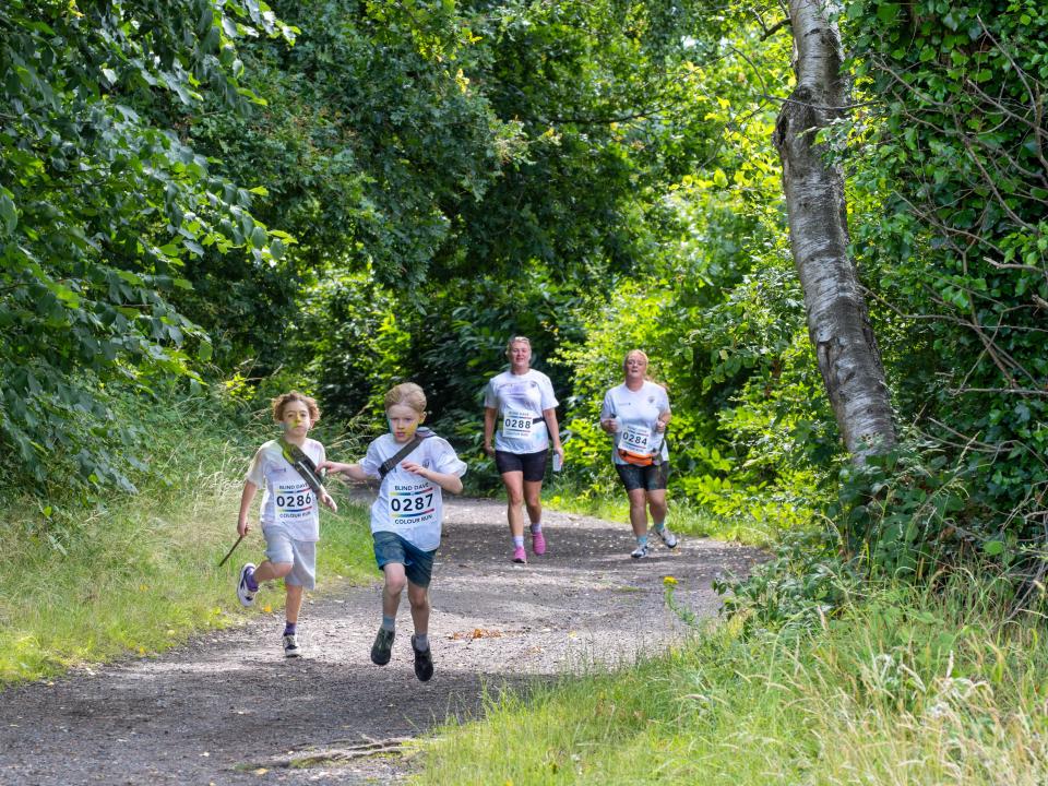 Four participants running the Sandwell Valley path, surrounded by trees.