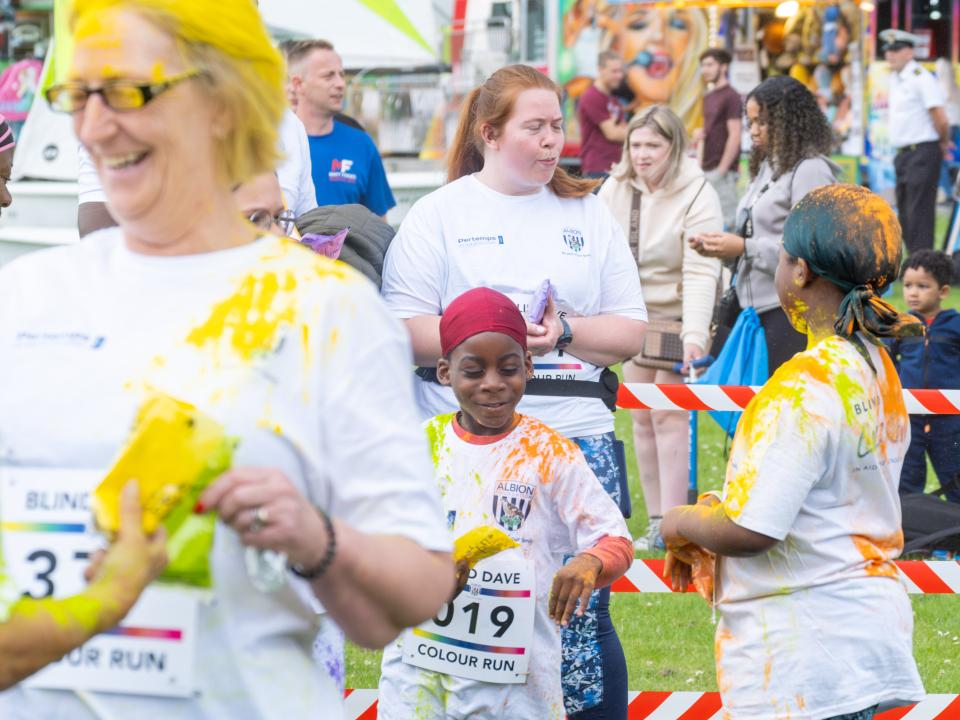 Group of participants and smiling inside barrier throwing paint powder.