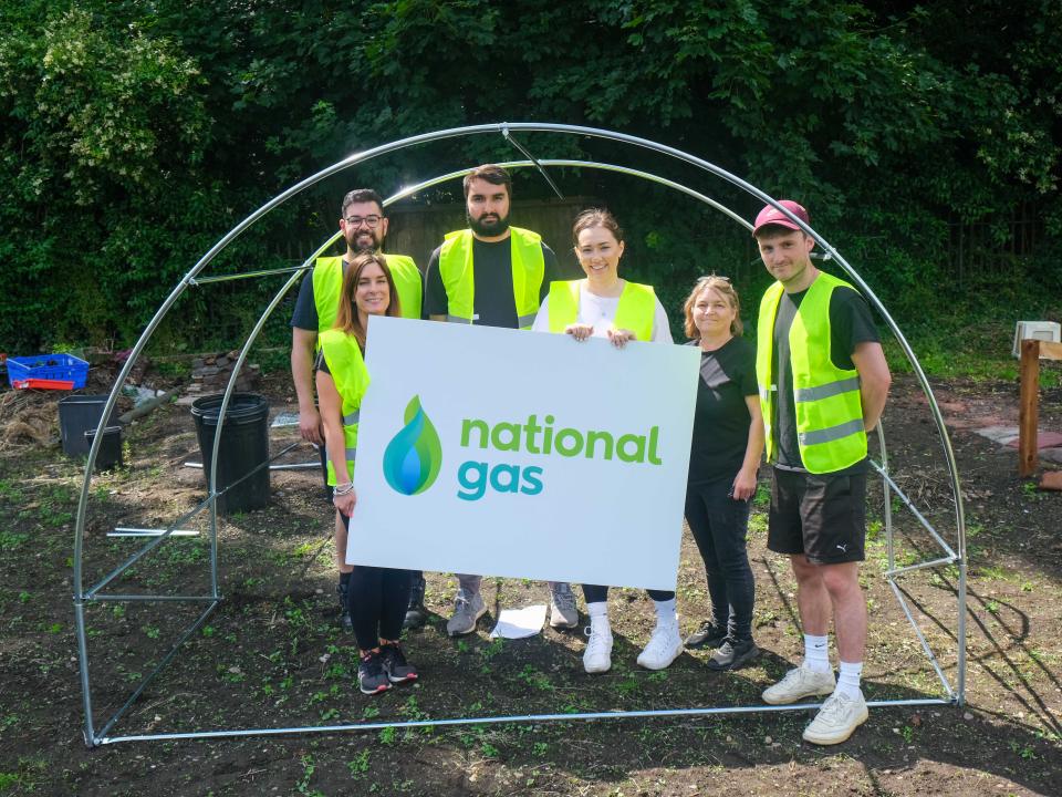 National Gas staff hold up their banner in-front of allotment infrastructure put up by staff.