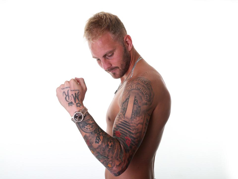 Uroš Račić posing for a photo showing off his tattoos on his arm 