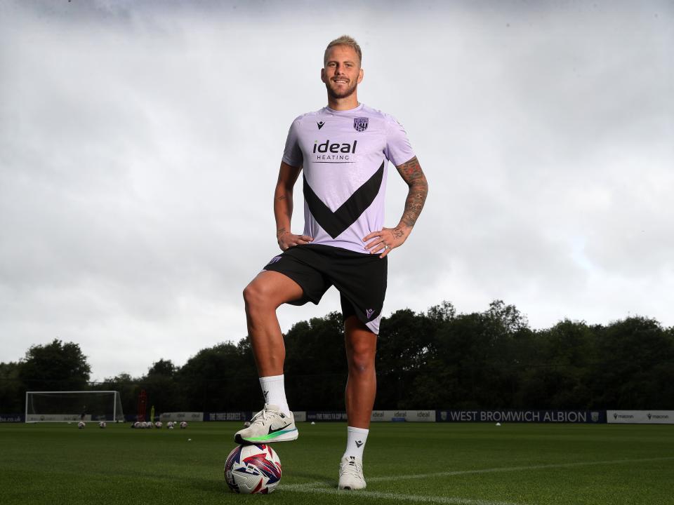 Uroš Račić smiling at the camera while stood with his foot on the ball out on a training pitch 