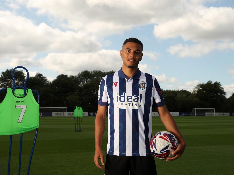 Lewis Dobbin looking at the camera while stood on the training pitch in a home shirt with a ball in his hand 