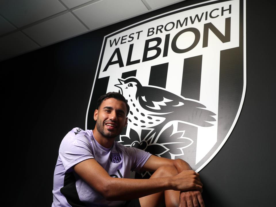 Gianluca Frabotta smiling at the camera while sat under a WBA badge 