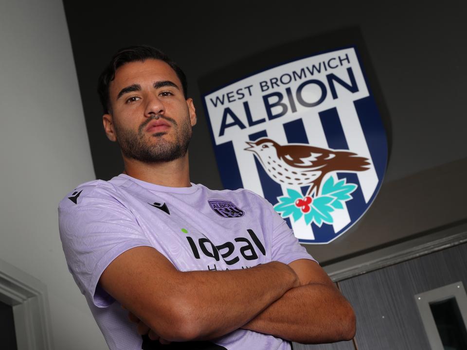 Gianluca Frabotta looking at the camera with his arms crossed while stood under a WBA badge 