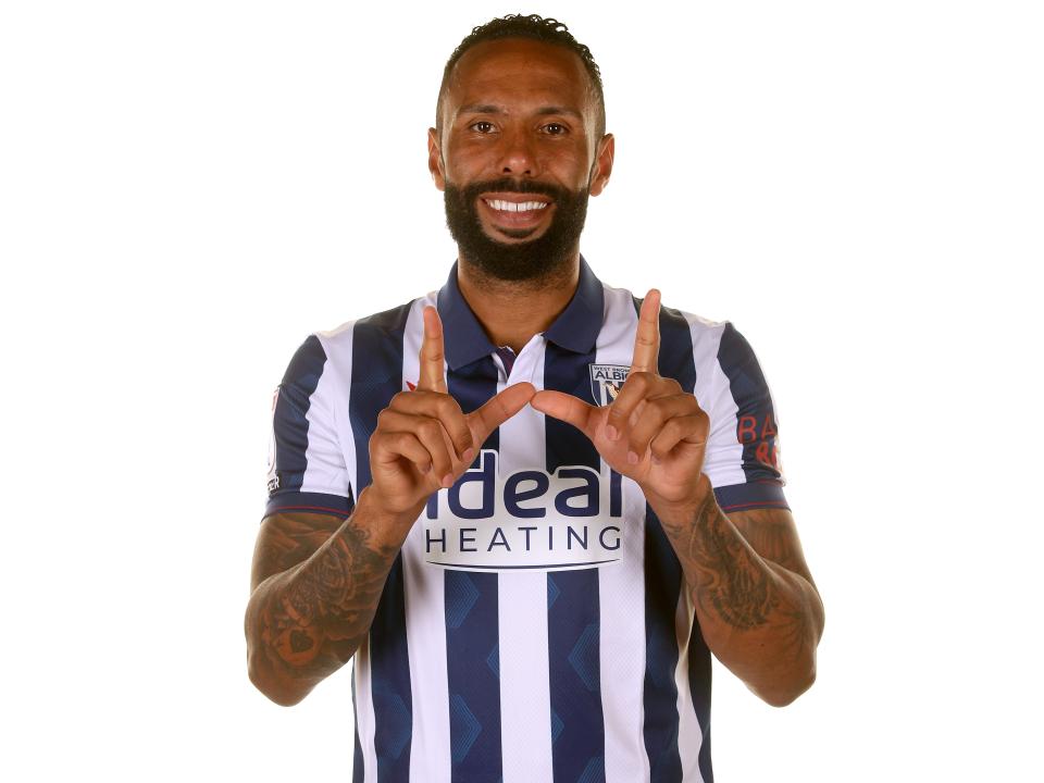 Kyle Bartley makes a 'W' sign while smiling at the camera in the home shirt 