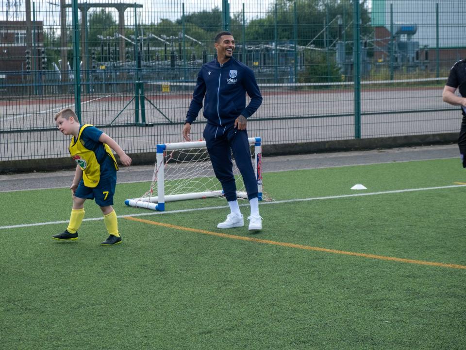 Karlan Grant plays football with camp participants.
