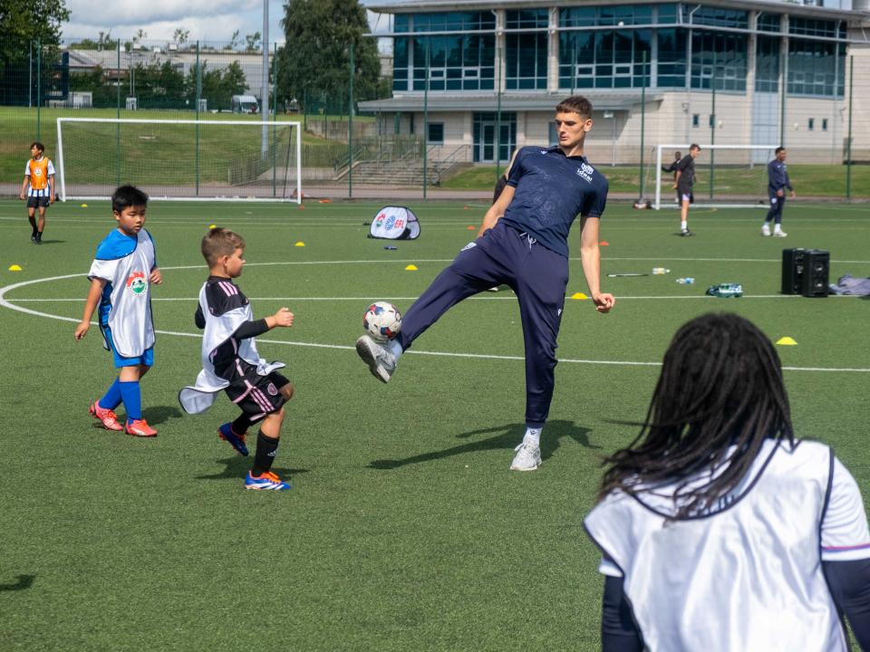 Caleb Taylor plays football with camp participants.