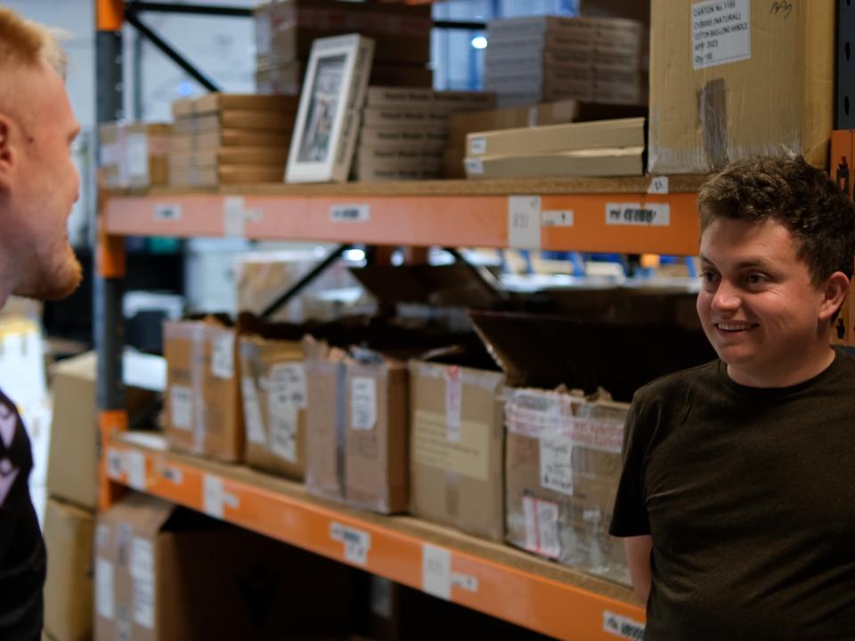 Jordy smiles, talking to the HATCH Project Coordinator during his shift at the Albion storage warehouse.