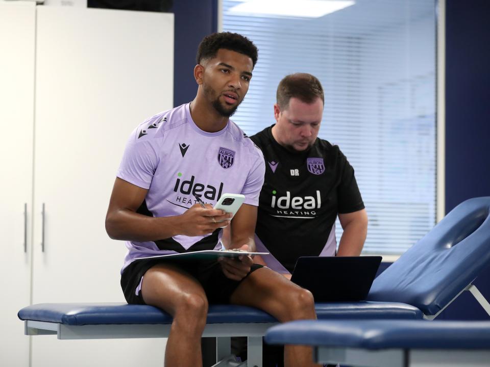 Mason Holgate sat on a physio bed with a member of staff