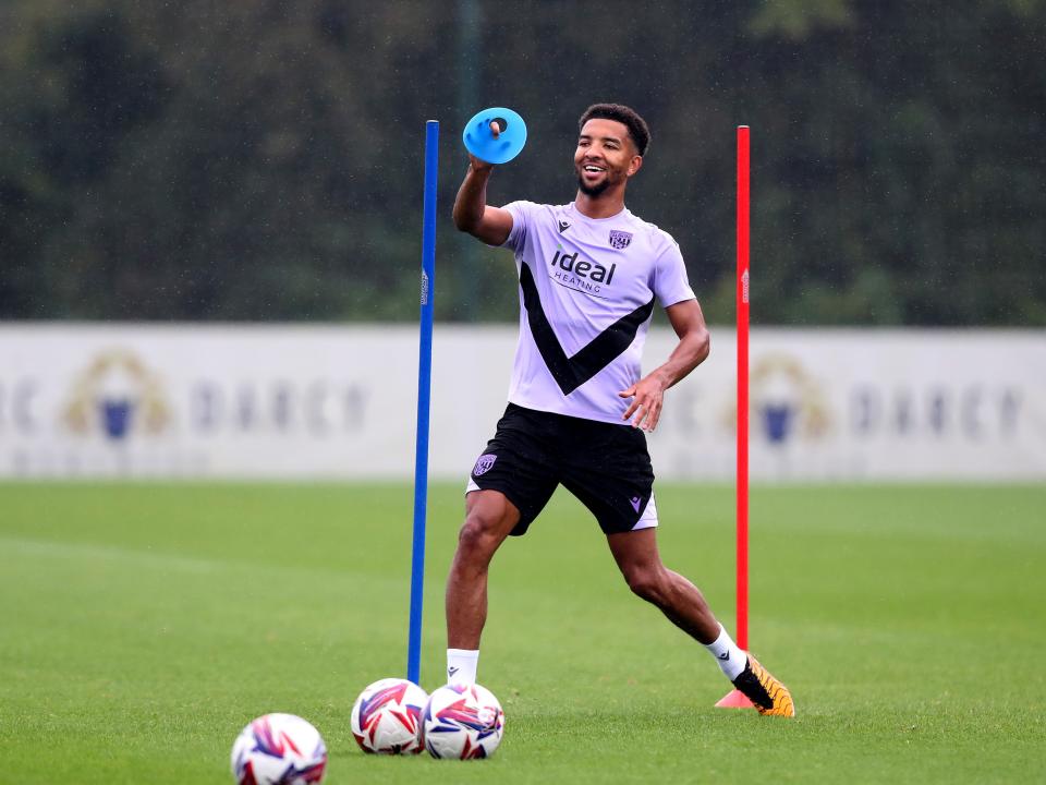 Mason Holgate smiling with a cone in his hand and three balls at his feet during a training session 