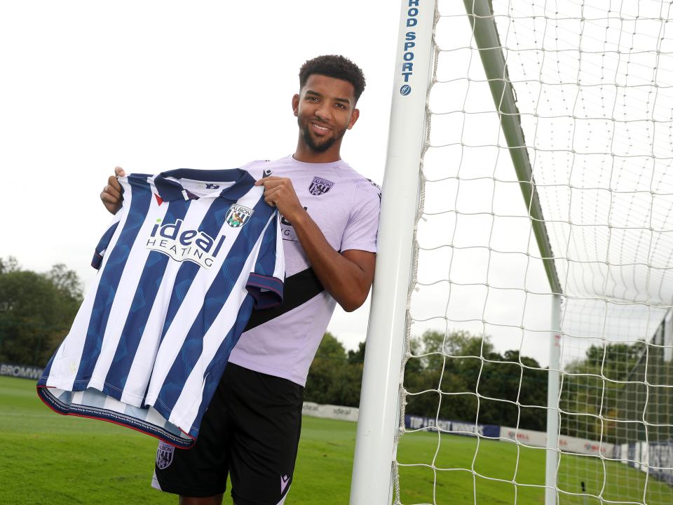 Mason Holgate smiling at the camera holding up a home shirt 