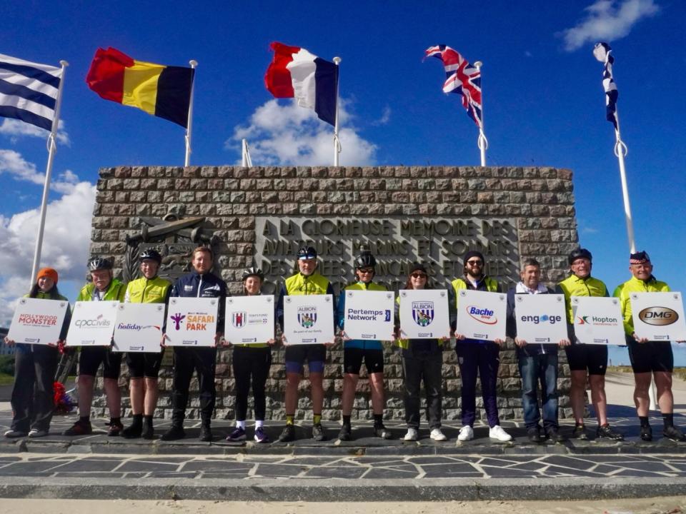 Team Blind Dave stand in front of the Dunkirk Memorial, bearing the names of sponsors for the challenge.