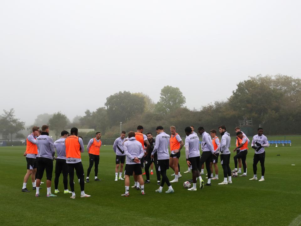 Albion's squad in a huddle on the training pitch listening to Carlos Corberán