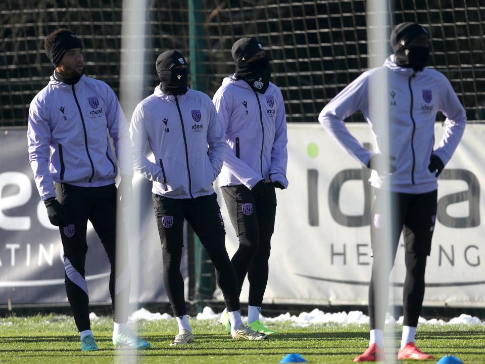 Four Albion players in snoods and hats watching training 