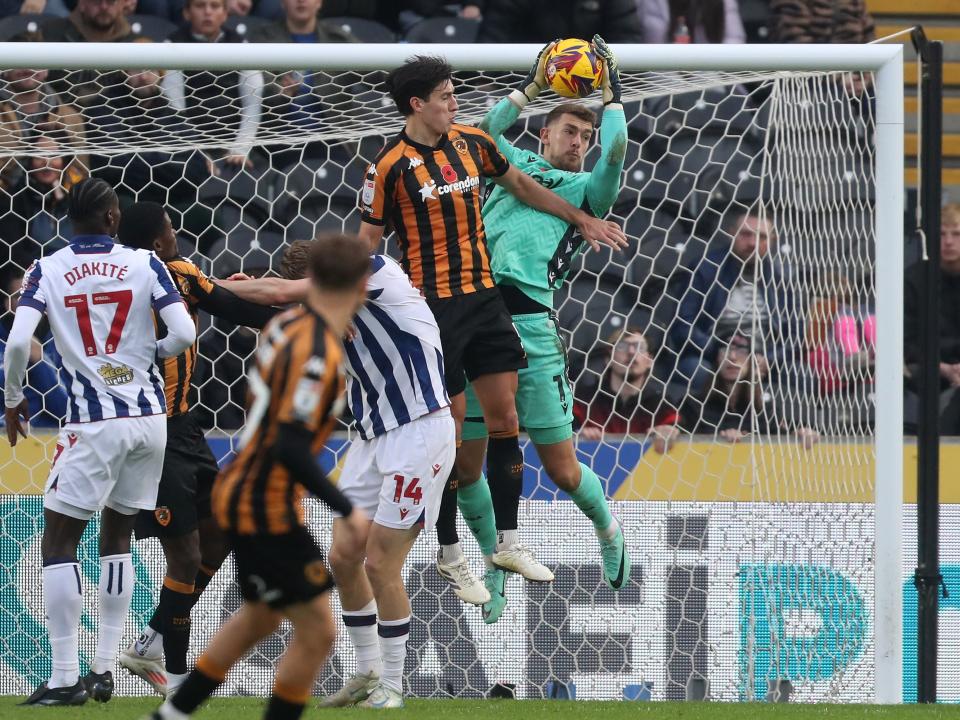 Alex Palmer jumps with a Hull player to try and win the ball