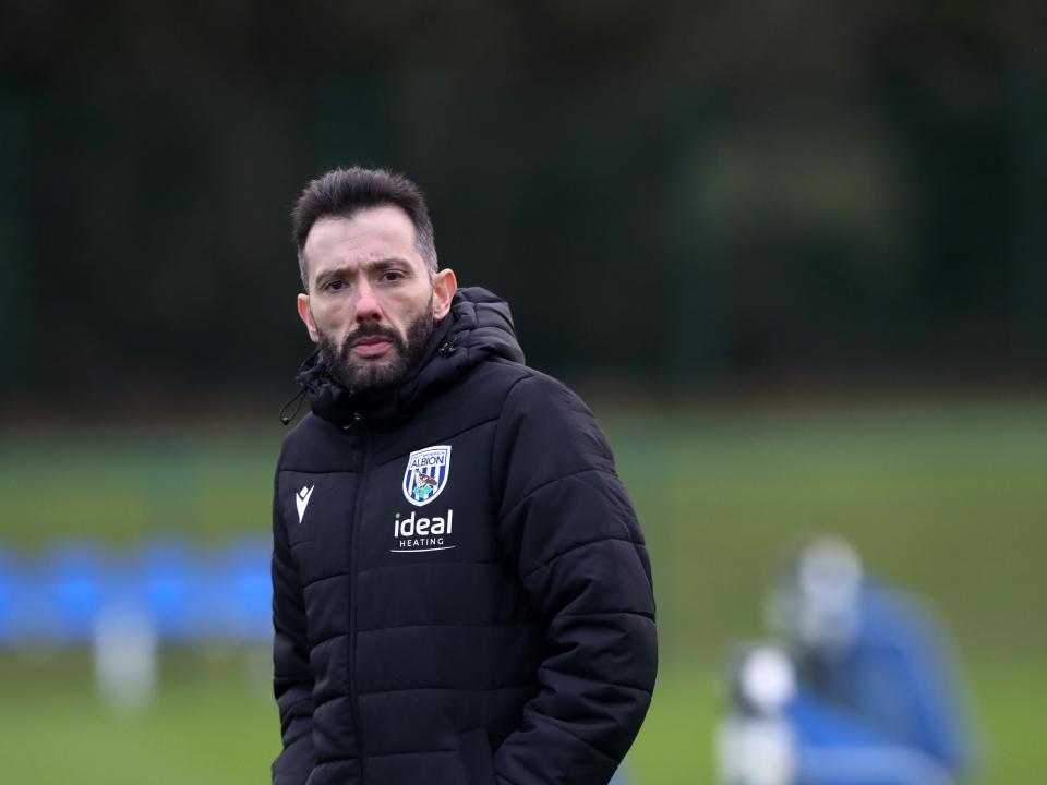 Carlos Corberán in a coat watching training 