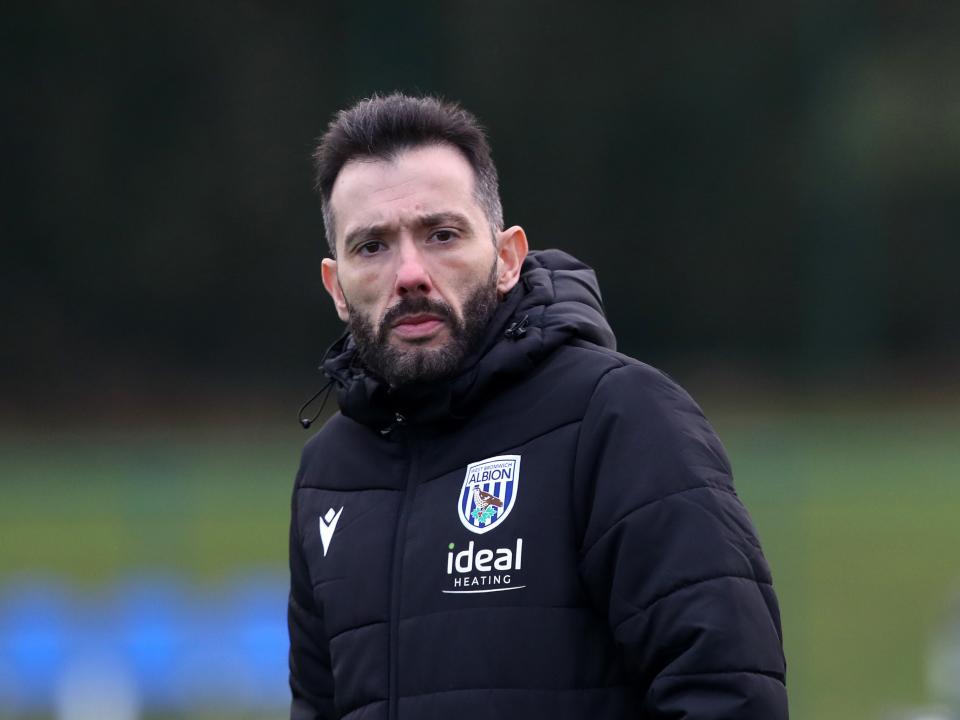 Carlos Corberán watching training in a black coat 
