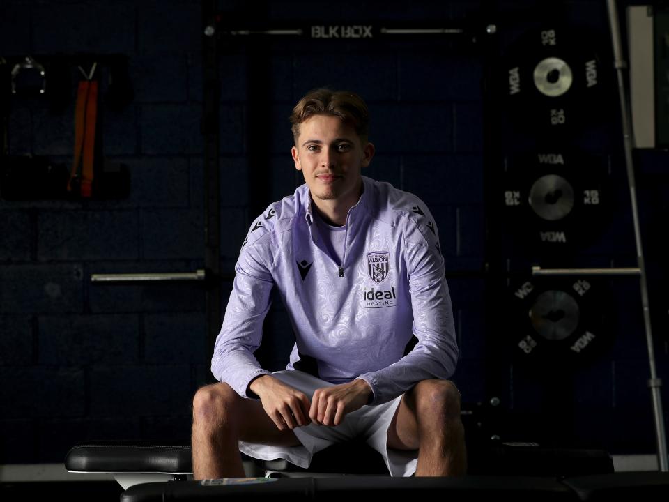 Isaac Price sat down in training gear smiling at the camera 