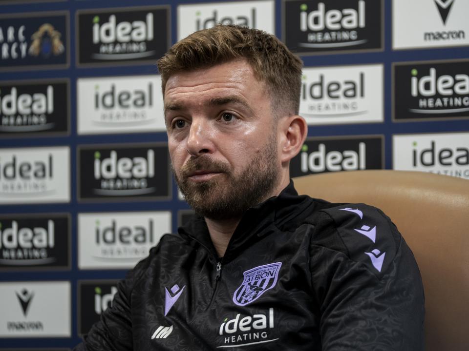 James Morrison is interviewed by the media in front of the press conference sponsor board