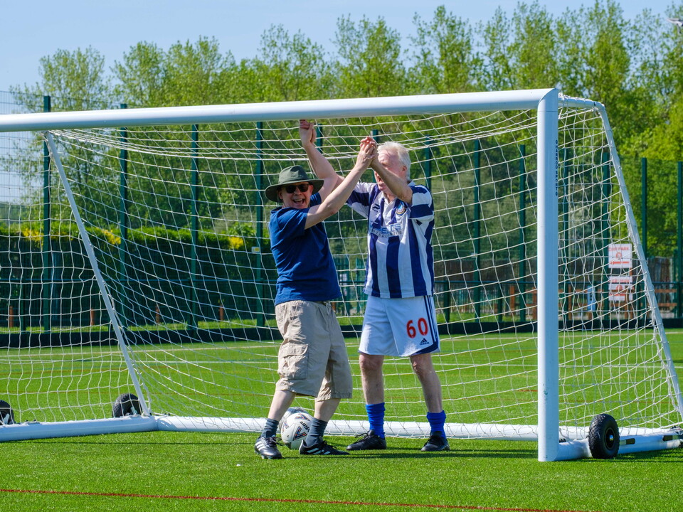 Two adult participants celebrating in front of goal