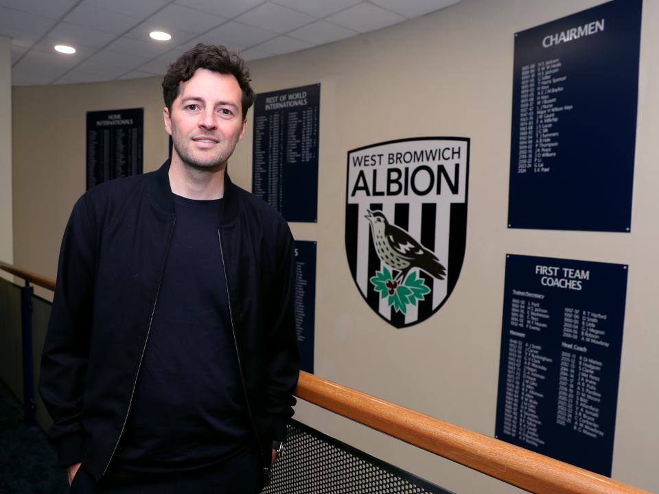 Ryan Mason posing for a photo stood in front of an Albion badge and honours board