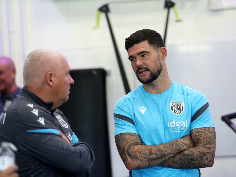 Alex Mowatt speaking to Nigel Gibbs in the gym with his arms crossed