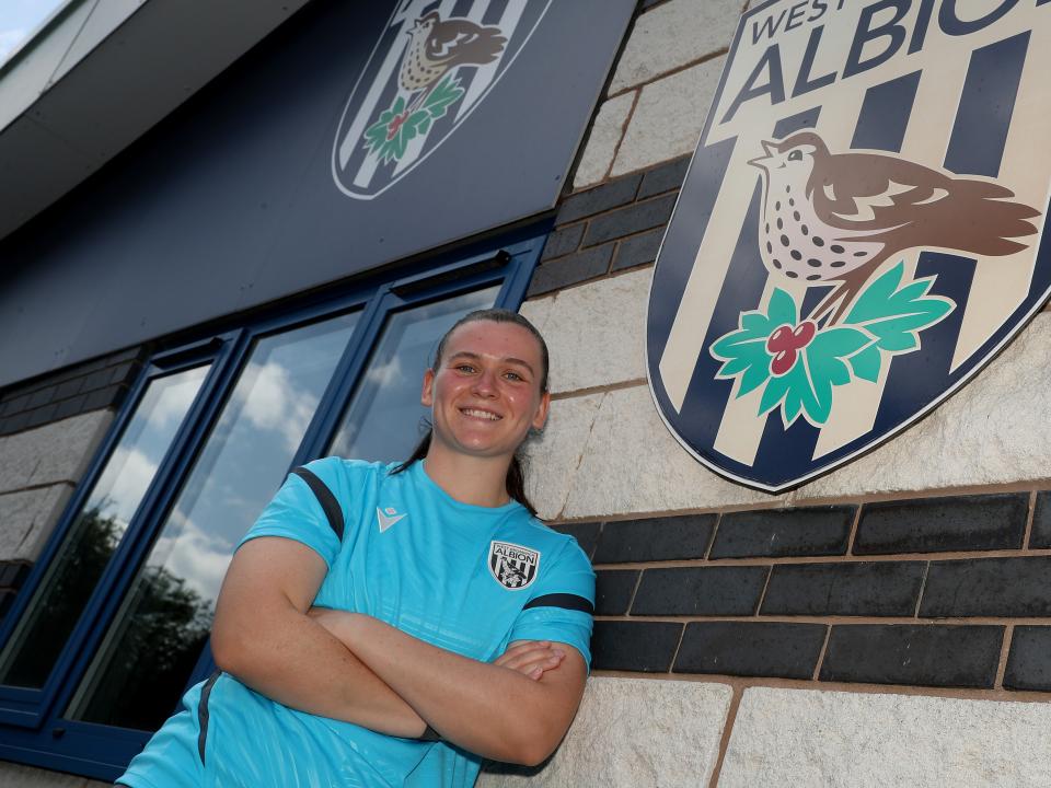 An image of Charlotte Clarke outside of Albion's training ground, next to a WBA badge