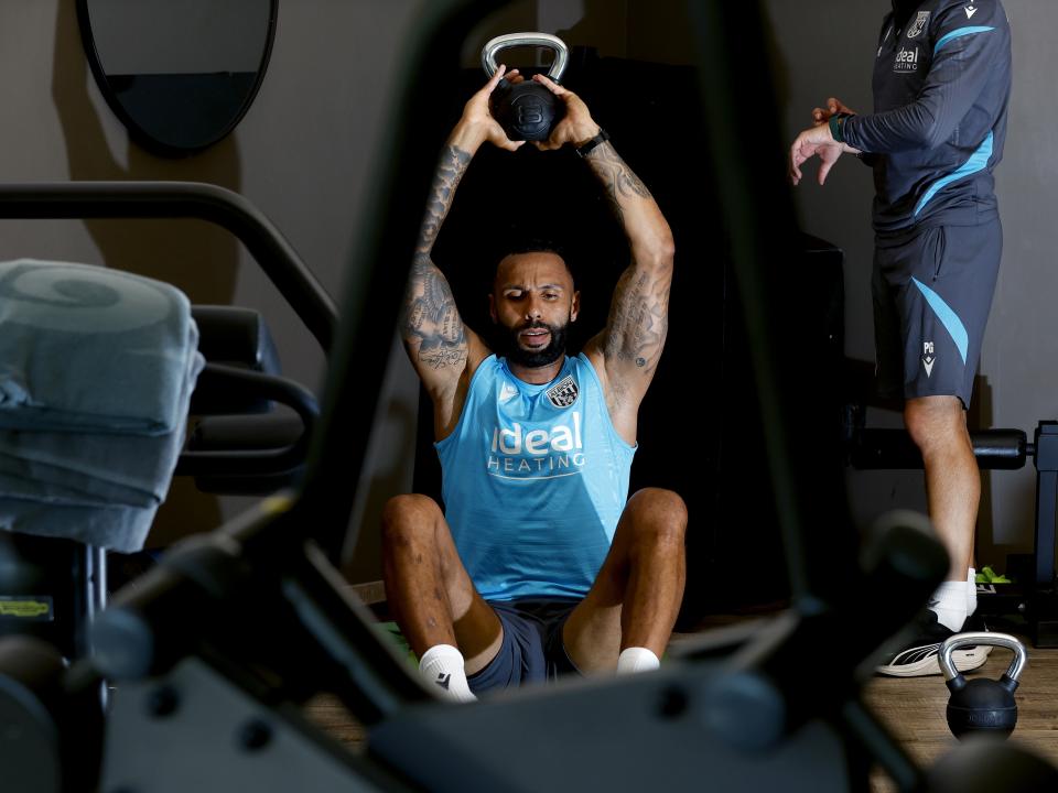 Kyle Bartley sat in the gym with a kettlebell weight above his head