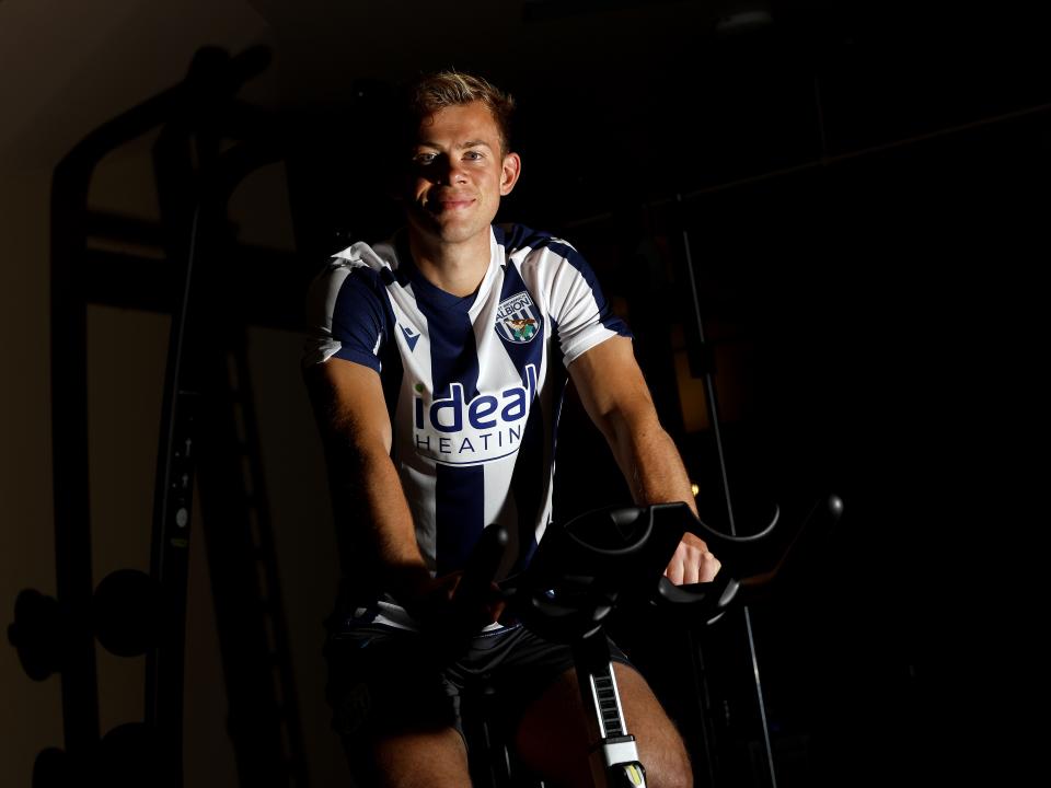 Aune Heggebø smiling at the camera while sat on a bike in the gym in a WBA shirt 