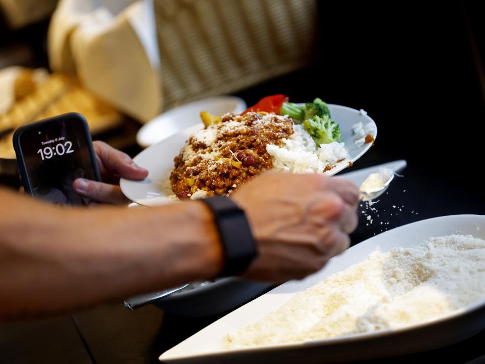 Dinner on a plate with mozzarella cheese being poured on