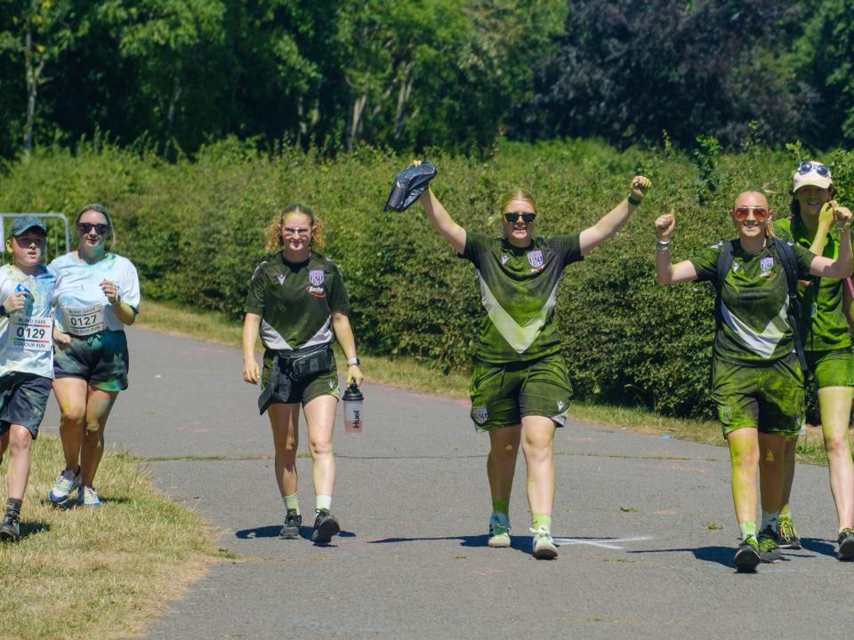 Four Foundation staff walking towards the finish line, with two have their arms raised. 