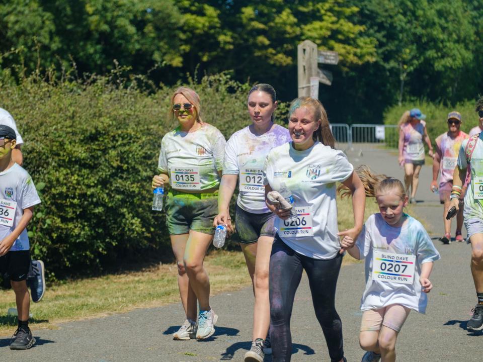 More runners smiling, heading towards the finish line.
