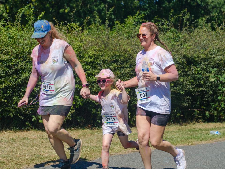 Two woman and a child holding hands heading towards the finish line.