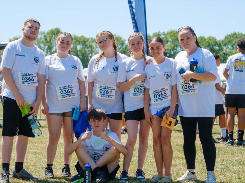 Group of seven participants, one sitting on the floor with thumbs up.