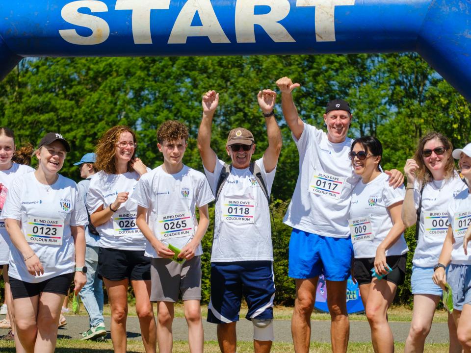 Group of participants under the starting arch, with a couple raising  their arms.
