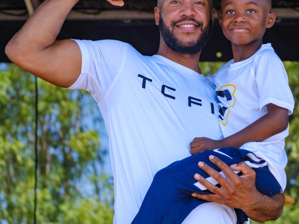TC Fit Tony holding this son and flexing.