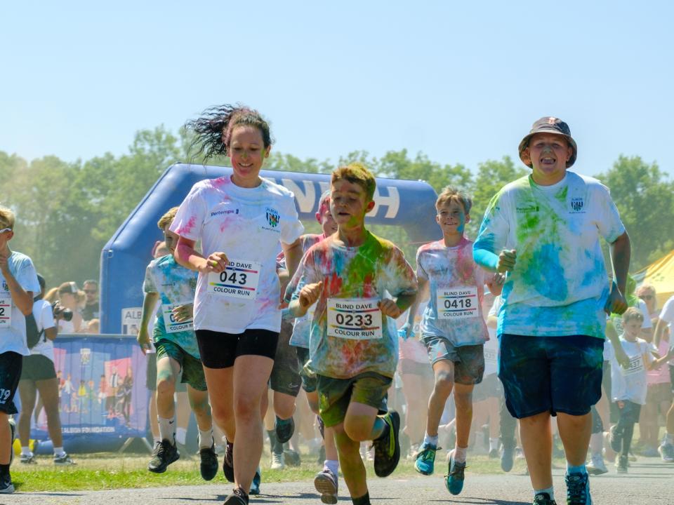 Runners covered in paint, leaving the start line.