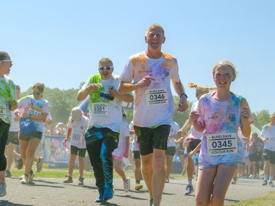 Runners covered in paint, all smiling.