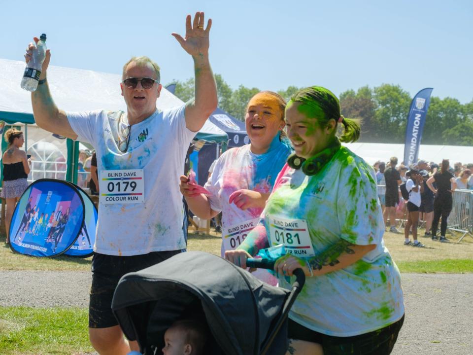 Three participants, one with a child in a push chair covered in paint. 