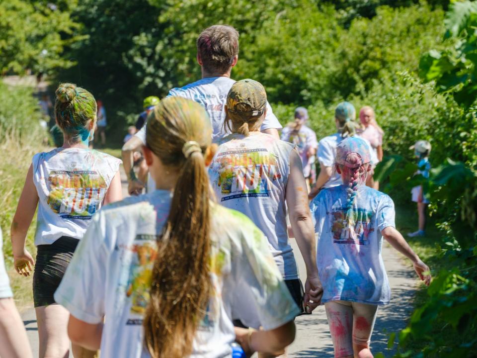 Backs of participants running through shaded greenery.