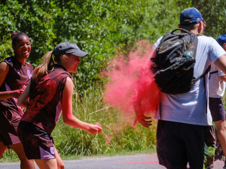 Two Foundation staff members aiming paint powder at a passing runner.