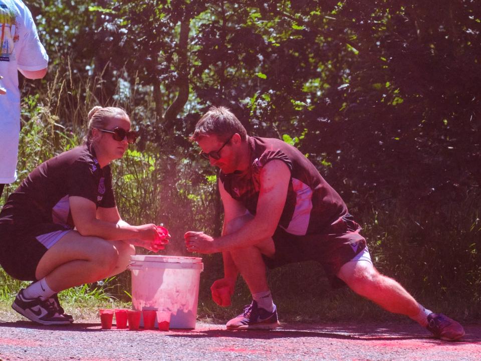 Close up of two Foundation staff members topping up their cups with paint powder.