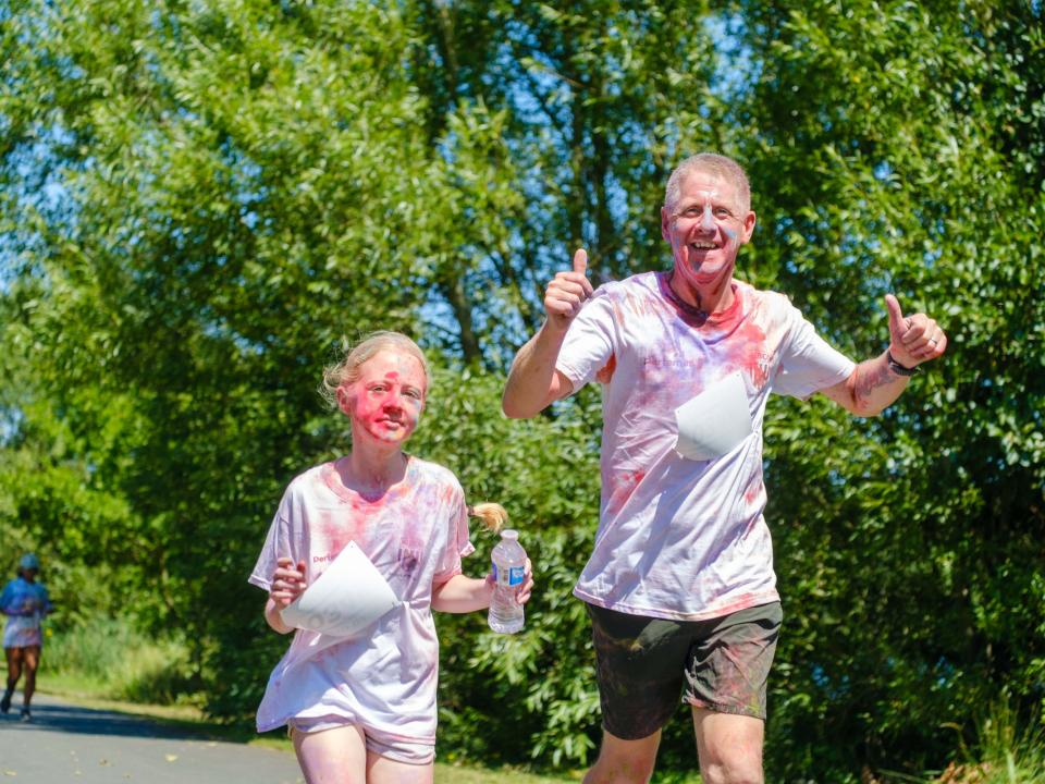 Father, with two thumbs up, and daughter running on the path.