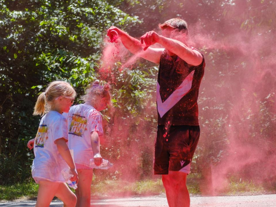 Foundation staff member dousing two young runners in red powder.