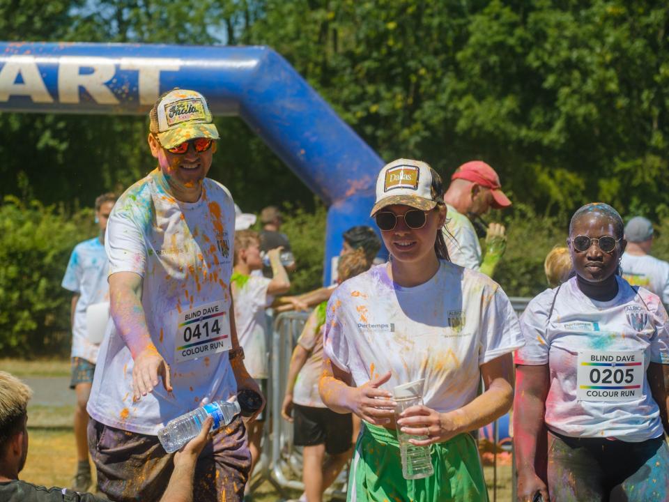 Two runners in trucker hats grabs bottles of water from Foundation staff at the end of the run.