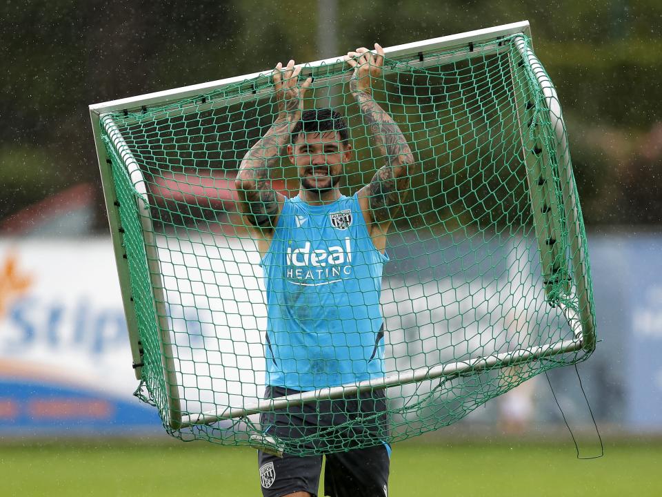 Alex Mowatt lifting a mini goal above his head in the rain during a training session