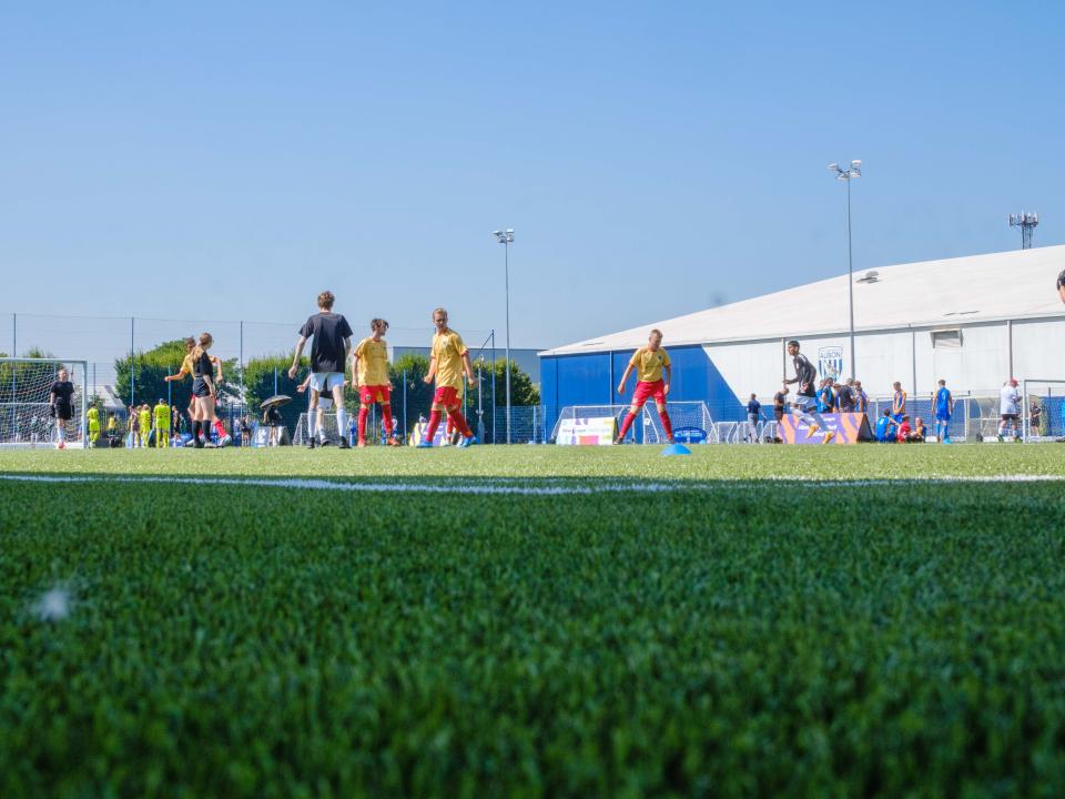 Wide shot of participants on the pitch with the Academy Dome in the background.