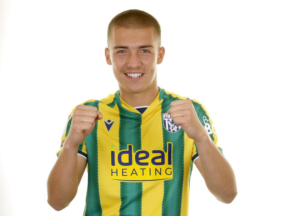 Alfie Gilchrist smiling at the camera while stood in a green and yellow shirt