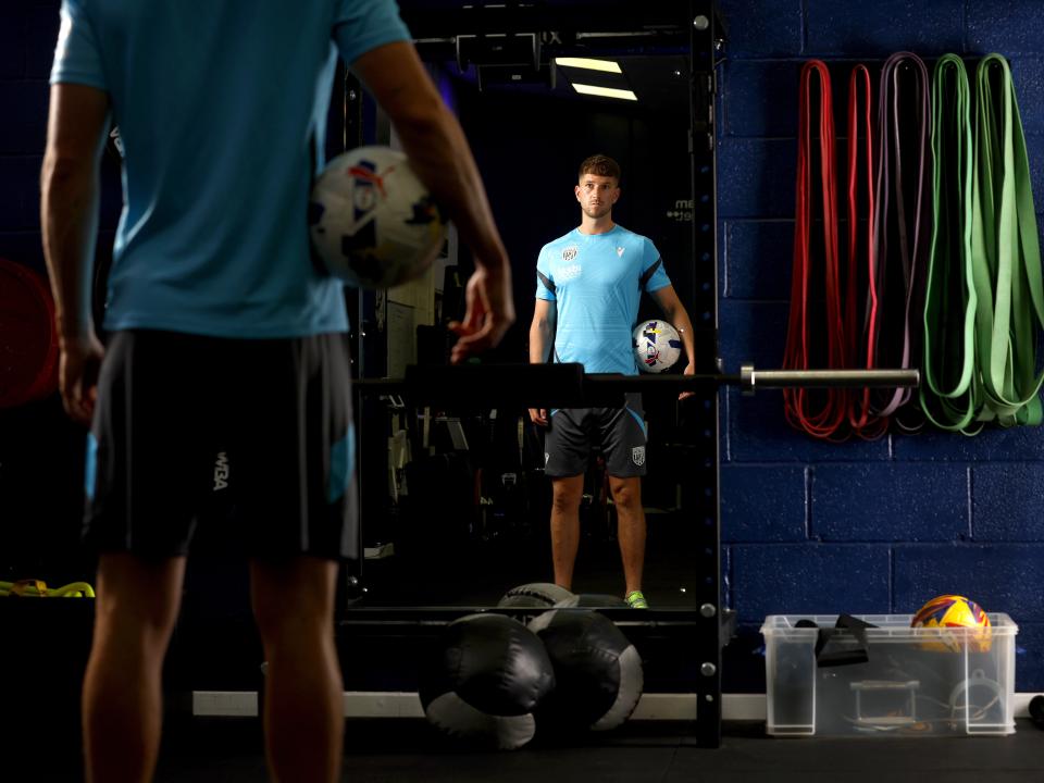 Chris Mepham holding a ball looking in the mirror in the gym